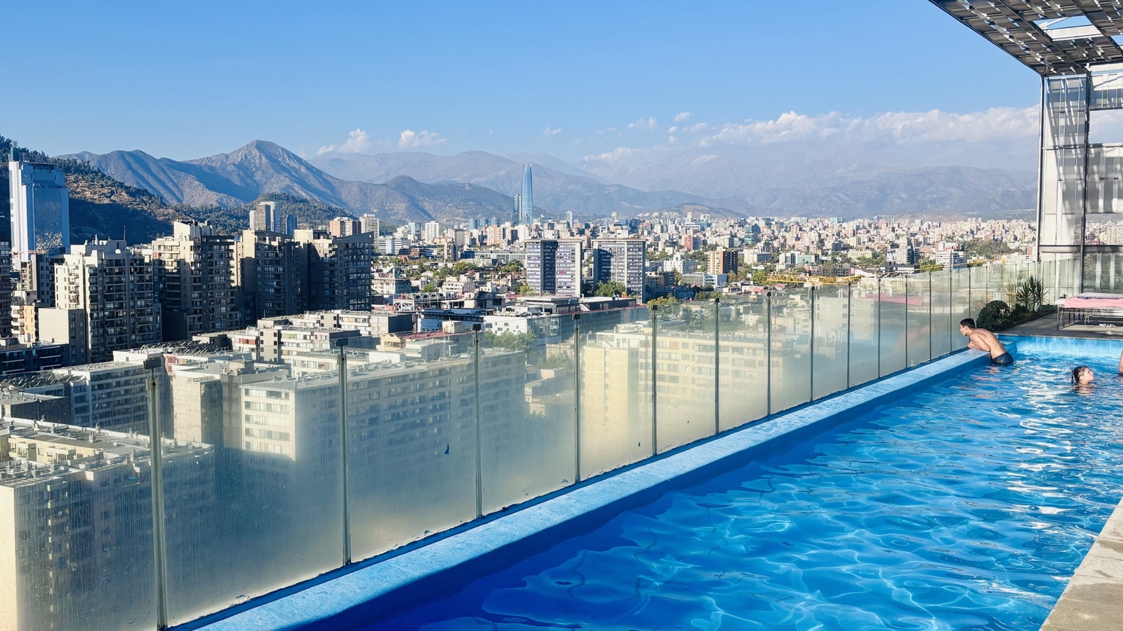 Personas en la piscina panorámica de Portugal Suites, con Santiago y la cordillera al fondo